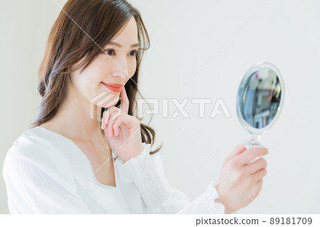 一個年輕女子用手鏡檢查粗糙的皮膚 89181709
