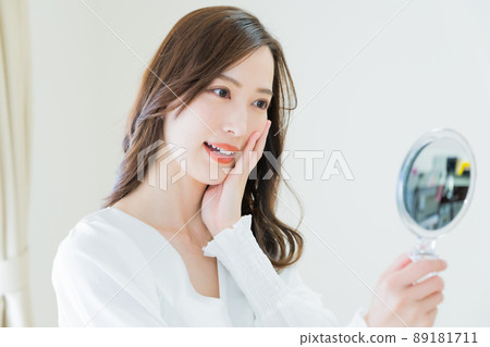 一個年輕女子用手鏡檢查粗糙的皮膚 89181711