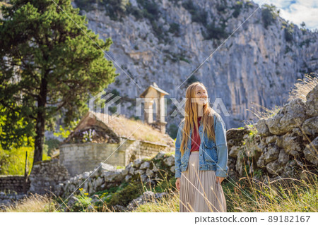 Woman tourist enjoys the view of Kotor. Montenegro. Bay of Kotor, Gulf of Kotor, Boka Kotorska and walled old city. Travel to Montenegro concept. Fortifications of Kotor is on UNESCO World Heritage 89182167