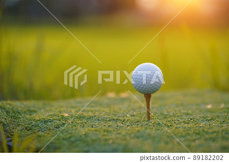 Golf ball is on tee at green lawn in a beautiful golf course with morning sunshine.Ready for golf in the first short. Golf ball is on tee at green lawn in a beautiful golf course with morning sunshine.Ready for golf in the first short. 89182202