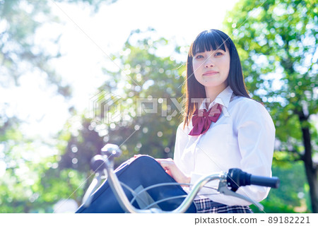 A high school girl looking up at the sky going to school by bicycle, a beautiful fresh green background, going to and from school A high school girl looking up at the sky going to school by bicycle, a beautiful fresh green background, going to and from school 89182221
