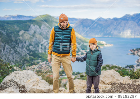 Dad and son travellers enjoys the view of Kotor. Montenegro. Bay of Kotor, Gulf of Kotor, Boka Kotorska and walled old city. Travel with kids to Montenegro concept. Fortifications of Kotor is on Dad and son travellers enjoys the view of Kotor. Montenegro. Bay of Kotor, Gulf of Kotor, Boka Kotorska and walled old city. Travel with kids to Montenegro concept. Fortifications of Kotor is on 89182287
