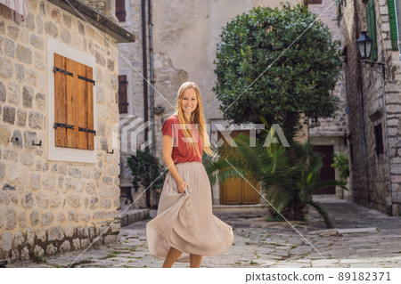 Woman tourist enjoying Colorful street in Old town of Kotor on a sunny day, Montenegro. Travel to Montenegro concept 89182371