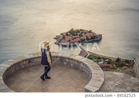 Woman tourist on background of beautiful view of the island of St. Stephen, Sveti Stefan on the Budva Riviera, Budva, Montenegro. Travel to Montenegro concept Woman tourist on background of beautiful view of the island of St. Stephen, Sveti Stefan on the Budva Riviera, Budva, Montenegro. Travel to Montenegro concept 89182525