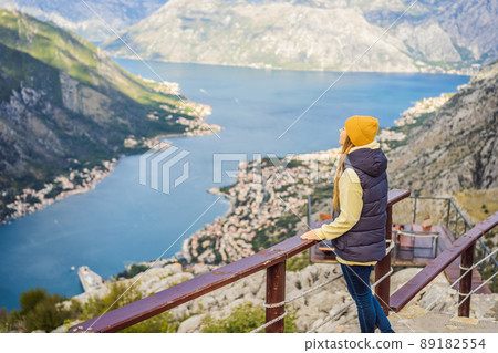 Woman tourist enjoys the view of Kotor. Montenegro. Bay of Kotor, Gulf of Kotor, Boka Kotorska and walled old city. Travel to Montenegro concept. Fortifications of Kotor is on UNESCO World Heritage 89182554