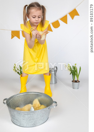 happy little girl with of small ducklings on a white background in the studio 89183179