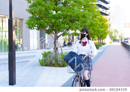 A high school girl who goes to school by bicycle passing near a shopping mall, a residential area, an urban area A high school girl who goes to school by bicycle passing near a shopping mall, a residential area, an urban area 89184339