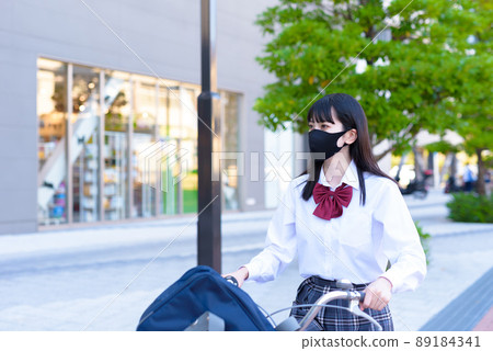 A high school girl who goes to school by bicycle passing near a shopping mall, a residential area, an urban area 89184341