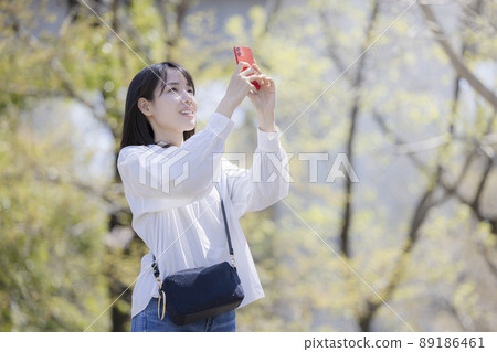 A young woman taking a picture with a smartphone 89186461