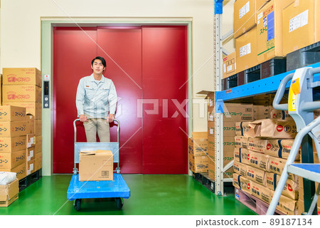 一名男子在貨梯前推著小車 一名男子在貨梯前推著小車 89187134