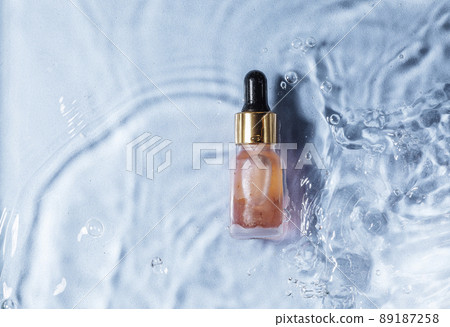 Mockup of cosmetic glass pink bottle with pipette and serum on water surface 89187258