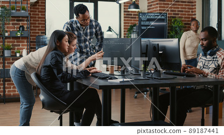 Programmers collaborating on group project compiling algorithm for new cloud computing user interface on computer screens. Mixed team of software engineers brainstorming ideas looking at running code. 89187441