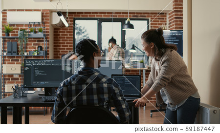 Two software developers doing high five hand gesture at desk with multiple screens running ai code celebrating successful algorithm. Programmers colleagues enjoying teamwork results in it agency. 89187447