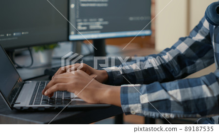 Closeup of programer hands typing machine learning code on laptop keyboard in front of computer screens with programming interface. System engineer writing algorithm for online cloud computing. 89187535