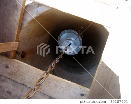 Old well with iron bucket on long forged chain for clean drinking water Old well with iron bucket on long forged chain for clean drinking water 89187991