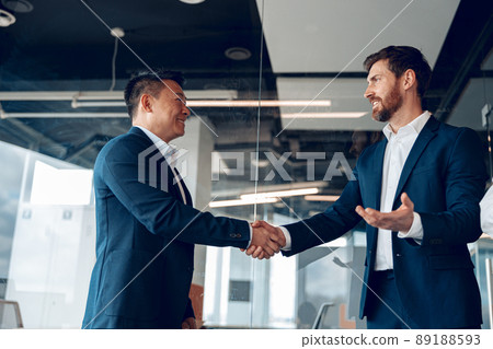 two mature diverse business partners are handshaking after successful deal in modern office 89188593