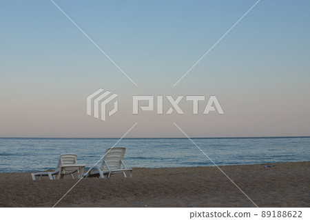 Two sunbeds on a sandy calm beach with turquoise sea water and white sand 89188622