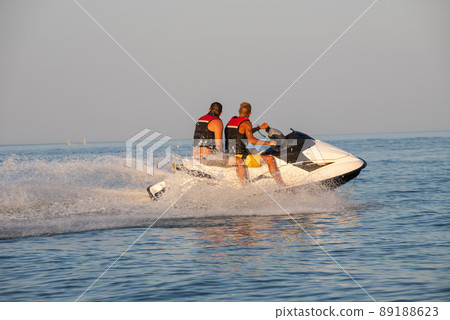 Teen age boy skiing on water scooter. Young man on personal watercraft in tropical sea. Active summer vacation for school child. Sport and ocean activity on beach holiday Teen age boy skiing on water scooter. Young man on personal watercraft in tropical sea. Active summer vacation for school child. Sport and ocean activity on beach holiday 89188623