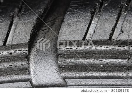 Old worn black tire with many large cracks in the car wheel. Old worn black tire with many large cracks in the car wheel. 89189178