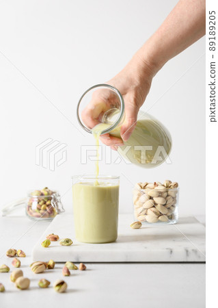 Pouring Pistachio milk in glass. Vegan plant based milk. 89189205