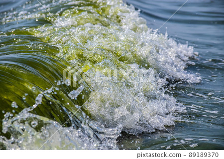 Sea wave with spray and foam near the shore Sea wave with spray and foam near the shore 89189370