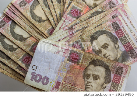 Ukrainian paper money is laid out on a blue background. 100 hryvnia banknotes Ukrainian paper money is laid out on a blue background. 100 hryvnia banknotes 89189490