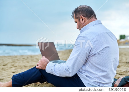 Serious confident mature man with laptop outdoors Serious confident mature man with laptop outdoors 89190058