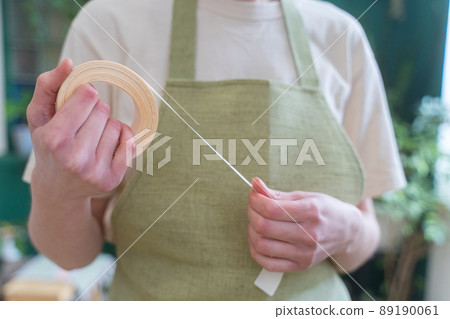 Decorative ribbon of beige color in the hands of a florist, close-up 89190061
