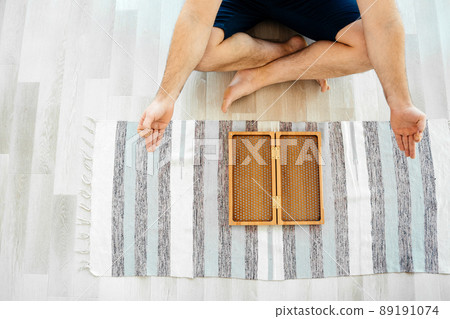 Cropped view of Man exercising yoga meditating and sitting on the floor near sadhu board 89191074