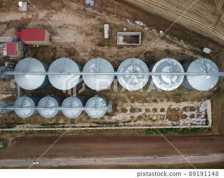 Grain elevator. Metal grain elevator in agricultural zone. Agriculture storage for harvest. Grain elevators on green nature background. Exterior of agricultural factory. Nobody. 89191148