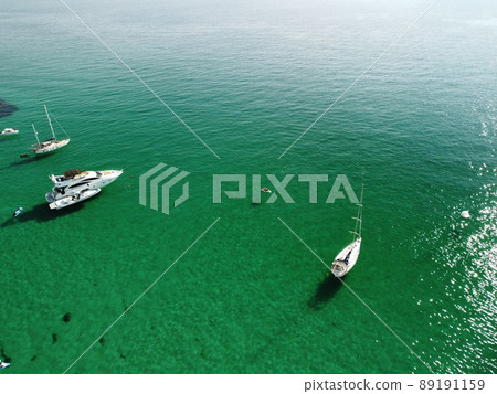Aerial panoramic view of seascape with crystal clear azure sea and rocky shores. Yachts in a beautiful lagoon on backdrop of rocks. The concept of an ideal destination for summer travel and vacation. Aerial panoramic view of seascape with crystal clear azure sea and rocky shores. Yachts in a beautiful lagoon on backdrop of rocks. The concept of an ideal destination for summer travel and vacation. 89191159