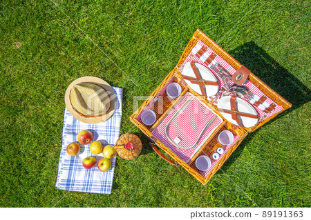 Picnic basket on green sunny lawn in the park Picnic basket on green sunny lawn in the park 89191363