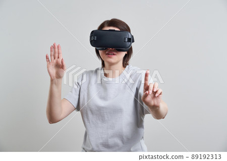 Happy young woman playing on VR glasses indoor, Virtual reality concept with young girl having fun with headset goggles, with copy space 89192313