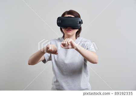 Happy young woman playing on VR glasses indoor, Virtual reality concept with young girl having fun with headset goggles, with copy space 89192335