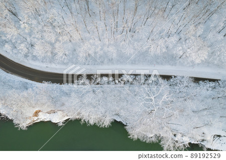 Aerial top down cinematic winter snow cowered country road, asphalt serpentine. Cars go traffic among forest. Aerial top down cinematic winter snow cowered country road, asphalt serpentine. Cars go traffic among forest. 89192529
