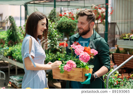 Worker helping female customer with plant in garden center 89193065