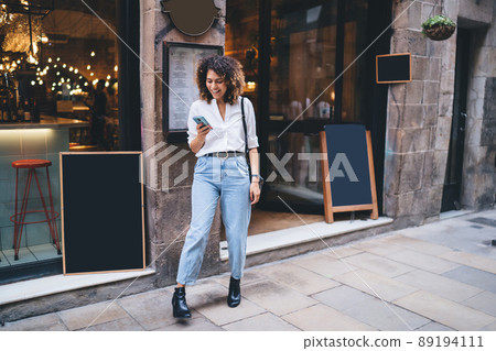 Happy hipster girl smiling while installing smartphone app for social network 89194111