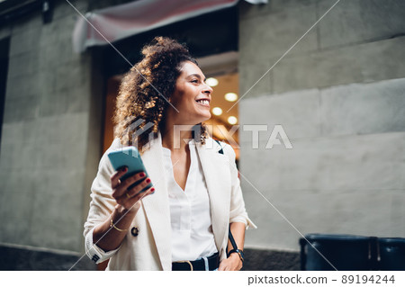 Happy female tourist with curly hair laughing during leisure time in city, Happy female tourist with curly hair laughing during leisure time in city, 89194244