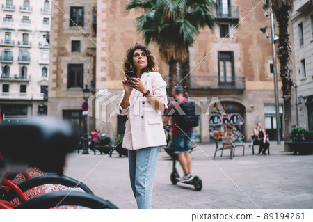 Trendy dressed tourist in earphones holding cellular Trendy dressed tourist in earphones holding cellular 89194261