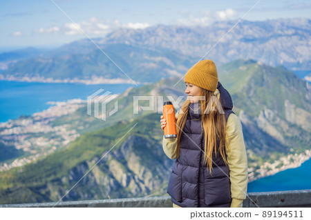 Woman tourist enjoys the view of Kotor. Montenegro. Bay of Kotor, Gulf of Kotor, Boka Kotorska and walled old city. Travel to Montenegro concept. Fortifications of Kotor is on UNESCO World Heritage 89194511