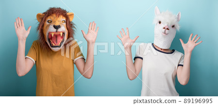 Young woman in lion and alpaca mask holding hands up showing open palms, stop or defense gesture Young woman in lion and alpaca mask holding hands up showing open palms, stop or defense gesture 89196995