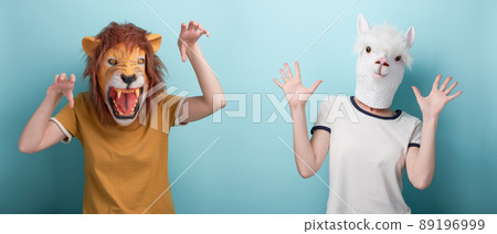 Woman in lion mask making attack gestures, and in alpaca mask showing open palms defense gesture Woman in lion mask making attack gestures, and in alpaca mask showing open palms defense gesture 89196999
