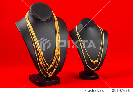 Necklace display stand with gold necklace on red Velvet fabric 89197638