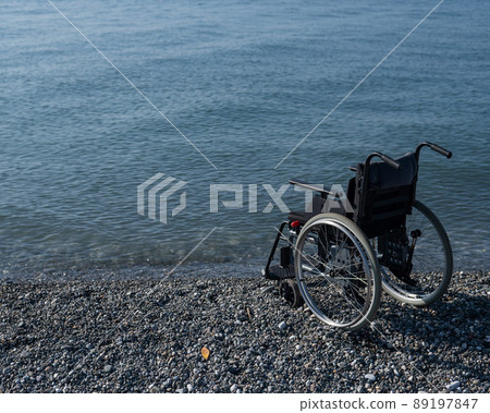 An empty wheelchair on a rocky seashore. An empty wheelchair on a rocky seashore. 89197847