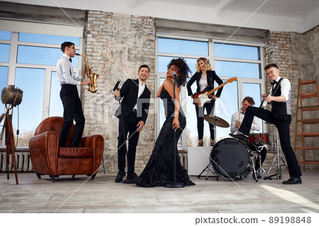 Repetition of multi ethnic jazz band in loft. Bass guitar player, electric guitar player, saxophonist and drummer at loft. Jazz music and jam session concept. passion for music and youth culture Repetition of multi ethnic jazz band in loft. Bass guitar player, electric guitar player, saxophonist and drummer at loft. Jazz music and jam session concept. passion for music and youth culture 89198848