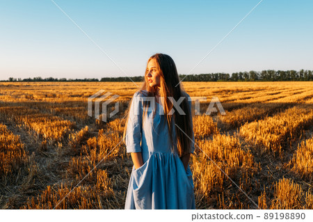 Escapism, getting away from it all, mental health, Stress resilience. Alone Young woman in linen dress walking on mowed wheat field at sunset. Peaceful woman with long hair spending time in nature Escapism, getting away from it all, mental health, Stress resilience. Alone Young woman in linen dress walking on mowed wheat field at sunset. Peaceful woman with long hair spending time in nature 89198890