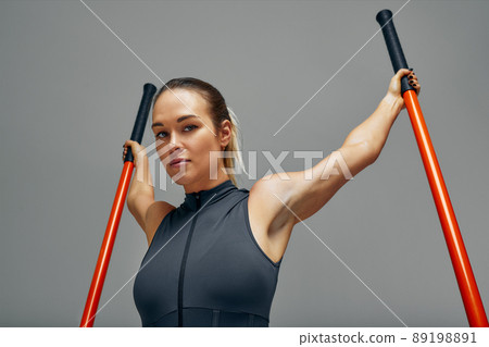 beautiful girl in sports uniform is training kung fu in the studio, fighter athlete, practicing martial arts with a stick beautiful girl in sports uniform is training kung fu in the studio, fighter athlete, practicing martial arts with a stick 89198891