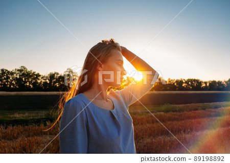 Escapism, getting away from it all, mental health, Stress resilience. Alone Young woman in linen dress walking on mowed wheat field at sunset. Peaceful woman with long hair spending time in nature Escapism, getting away from it all, mental health, Stress resilience. Alone Young woman in linen dress walking on mowed wheat field at sunset. Peaceful woman with long hair spending time in nature 89198892