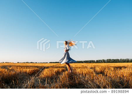 Escapism, getting away from it all, mental health, Stress resilience. Alone Young woman in linen dress walking on mowed wheat field at sunset. Peaceful woman with long hair spending time in nature Escapism, getting away from it all, mental health, Stress resilience. Alone Young woman in linen dress walking on mowed wheat field at sunset. Peaceful woman with long hair spending time in nature 89198894
