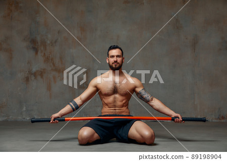 A ninja man holds on to a fighting stick and attacks close-up on gray studio background 89198904